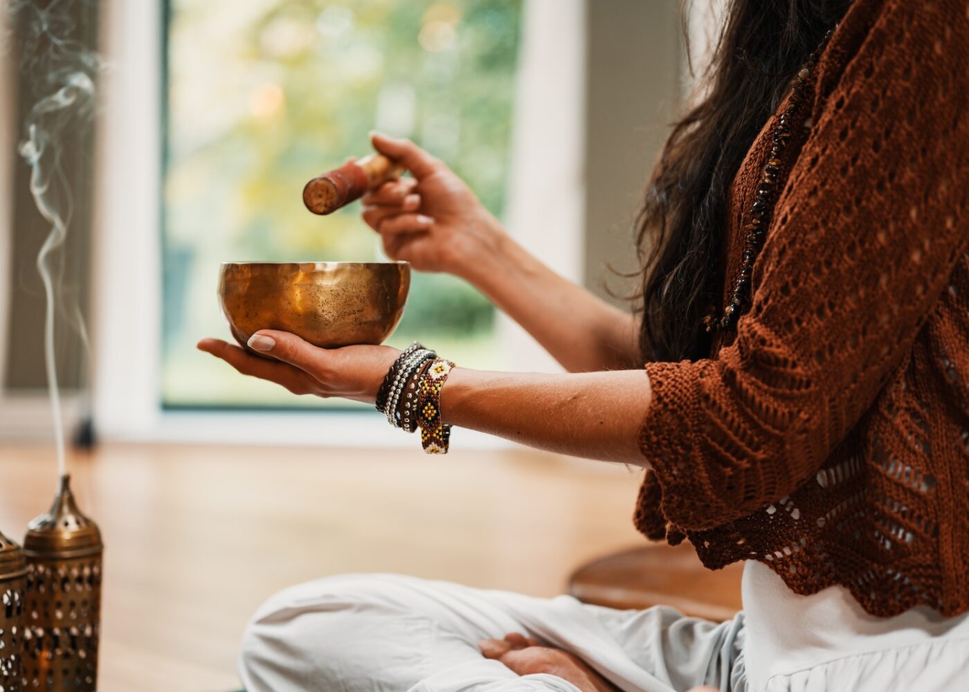 woman in brown knit sweater holding brown ceramic cup